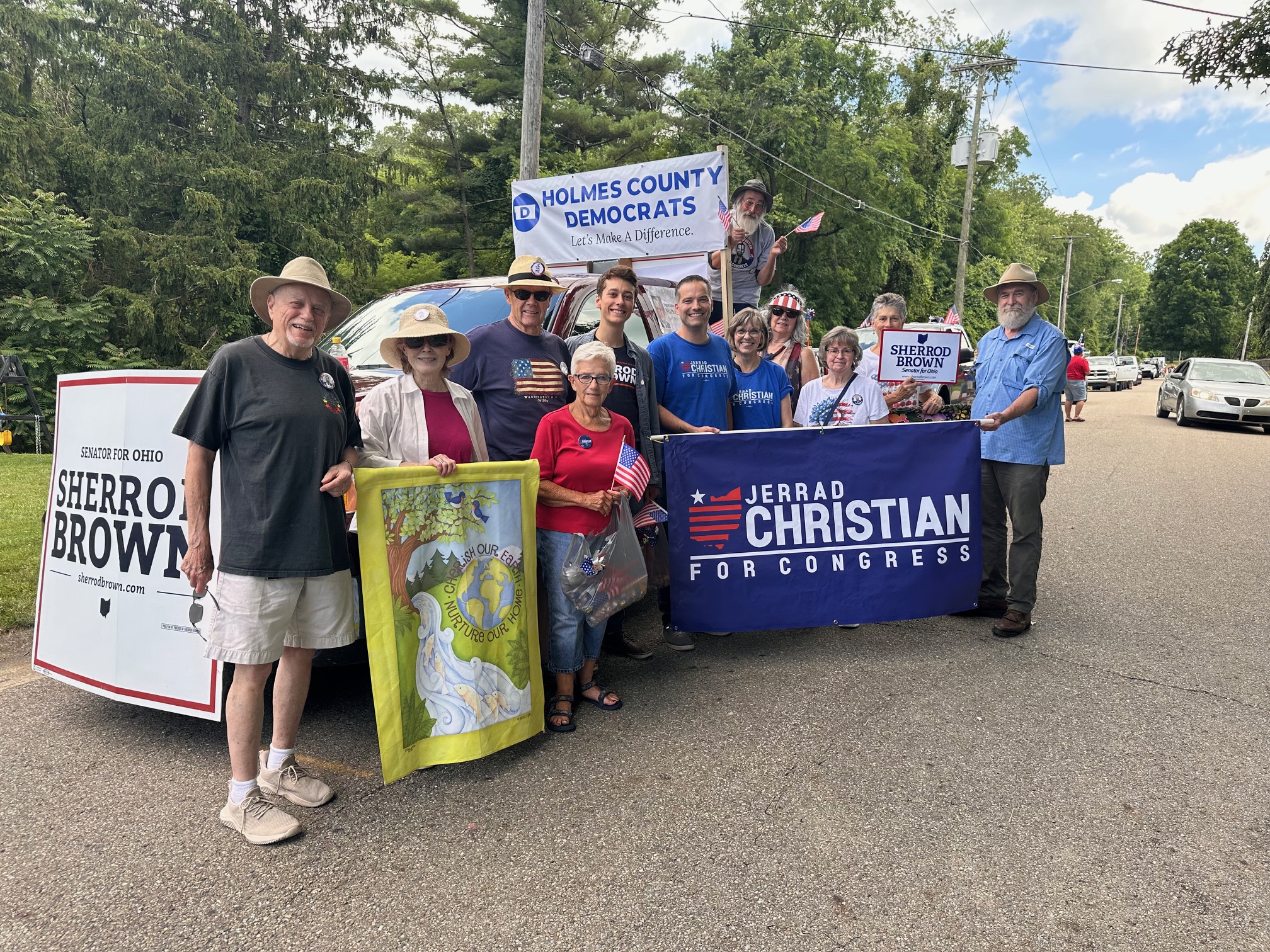 A group of people pose in front of a parade float holding political candidate support signs. 